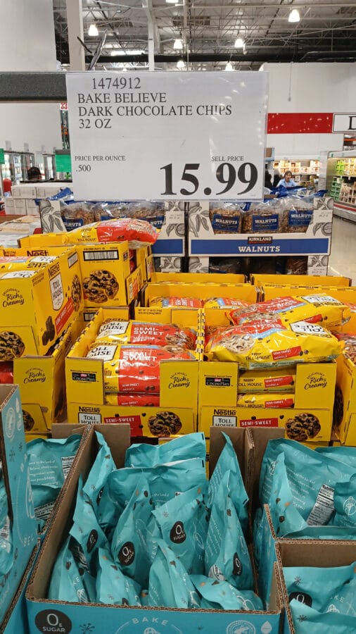 Costco display of Bake Believe dark chocolate chips with a $15.99 price sign and walnuts in the background