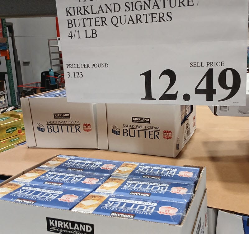 Costco warehouse display of Kirkland Signature salted sweet cream butter quarters with a $12.49 price sign