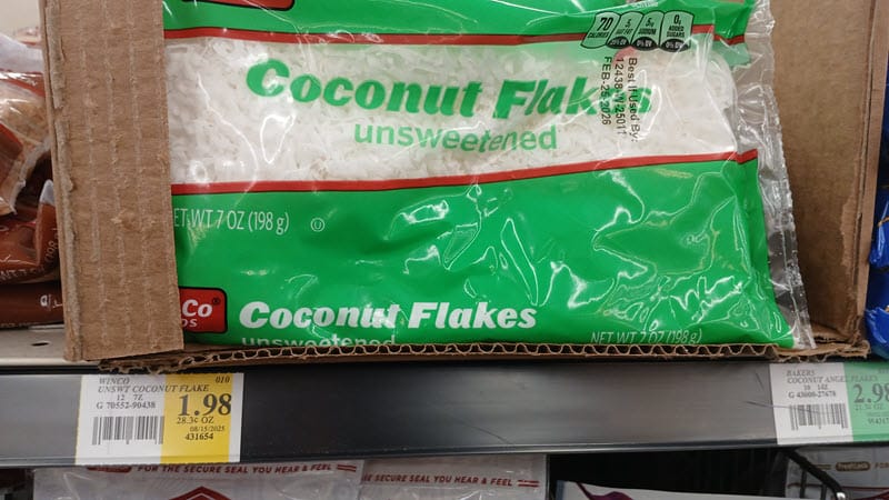 Bag of WinCo unsweetened coconut flakes on a store shelf with a $1.98 price tag