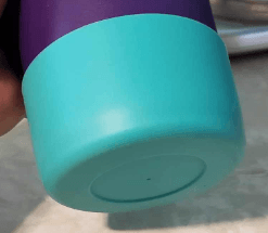 Teal silicone protective boot fitted on the bottom of a purple tumbler