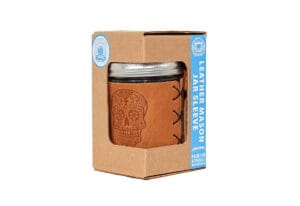 Leather mason jar sleeve with a sugar-skull design displayed in a kraft retail box