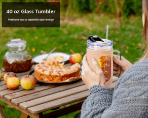 Person holding a 40 oz glass tumbler outdoors beside an apple pie and fresh apples