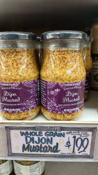 Trader Joe&rsquo;s Whole Grain Dijon Mustard jars on a store shelf with a $1.99 price tag