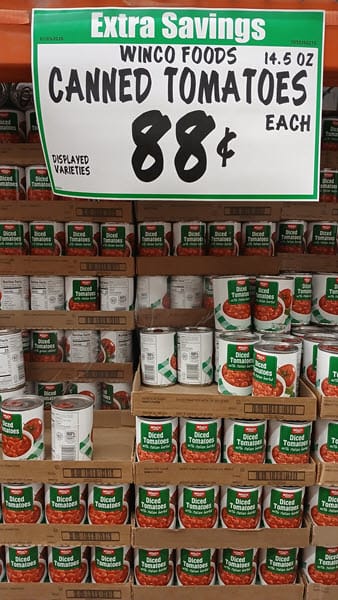 WinCo Foods display of canned diced tomatoes with an 88-cents price sign