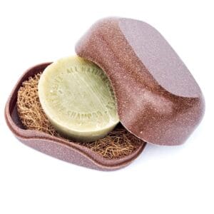 Shampoo bar resting on a coir pad inside a brown speckled travel soap case
