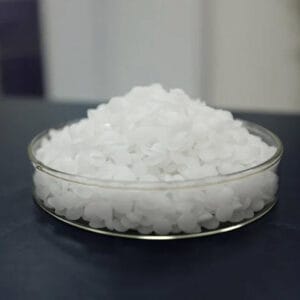 White caustic soda (sodium hydroxide lye) pellets in a clear glass dish
