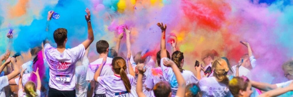 Crowd of runners at a color run throwing clouds of bright powdered pigment into the air