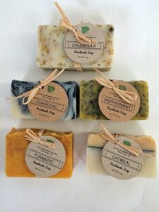 Five handmade soap bars finished with kraft-paper hang tags, labeled Calendula, Charcoal, Peppermint, Turmeric, and Oatmeal